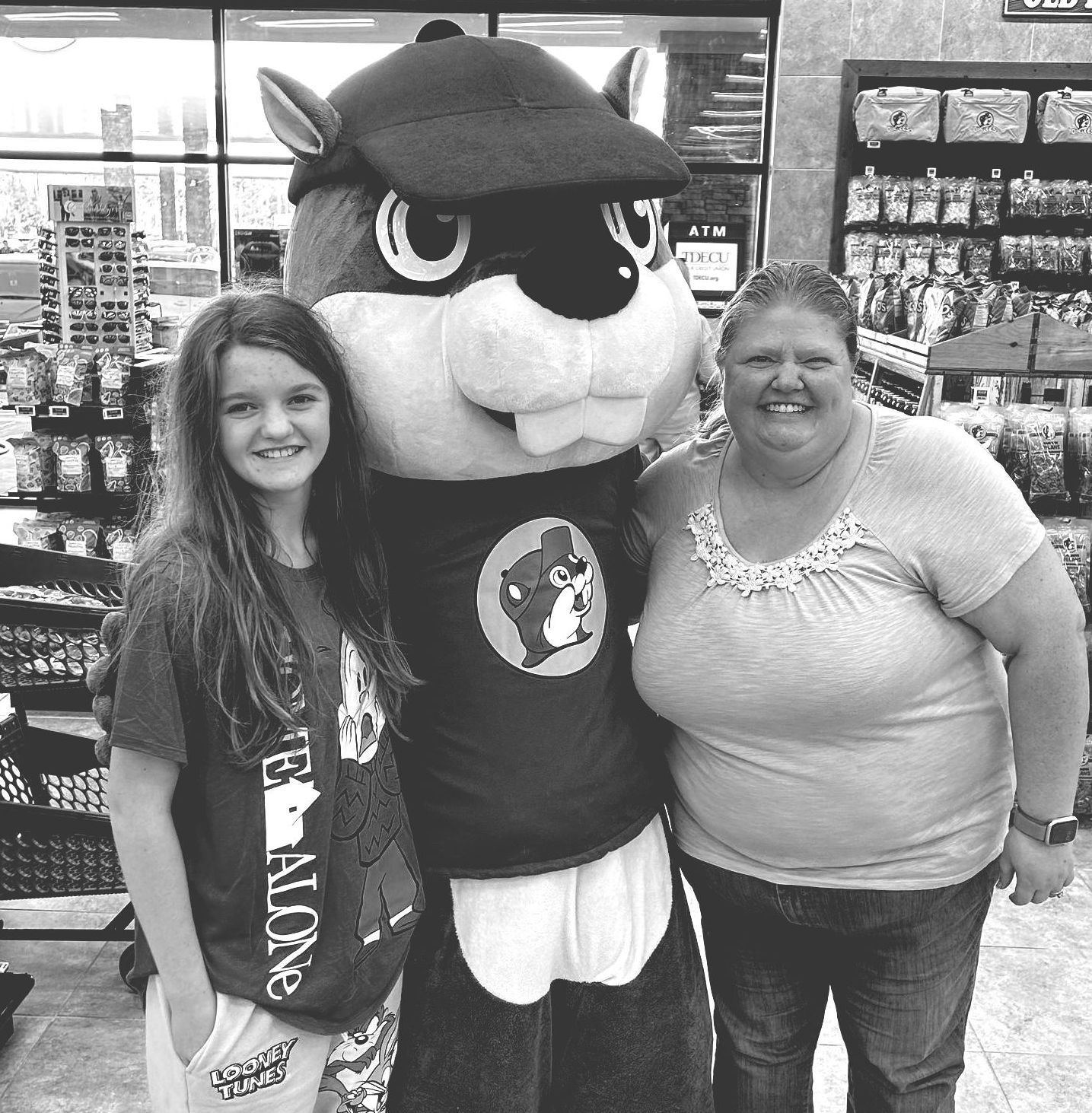 a black and white photo of two women and a mascot in a store