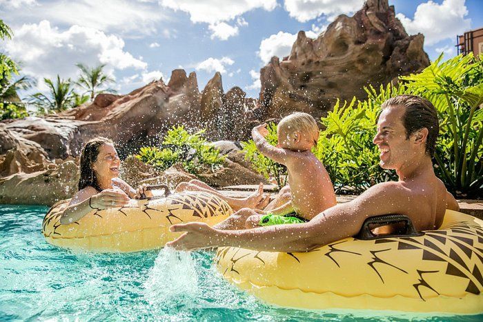a man and two children are floating on tubes in a pool .