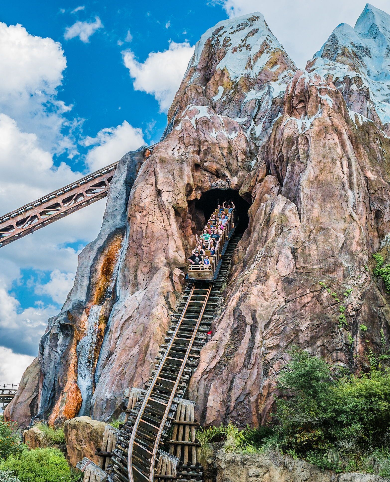 a roller coaster is going up the side of a mountain .