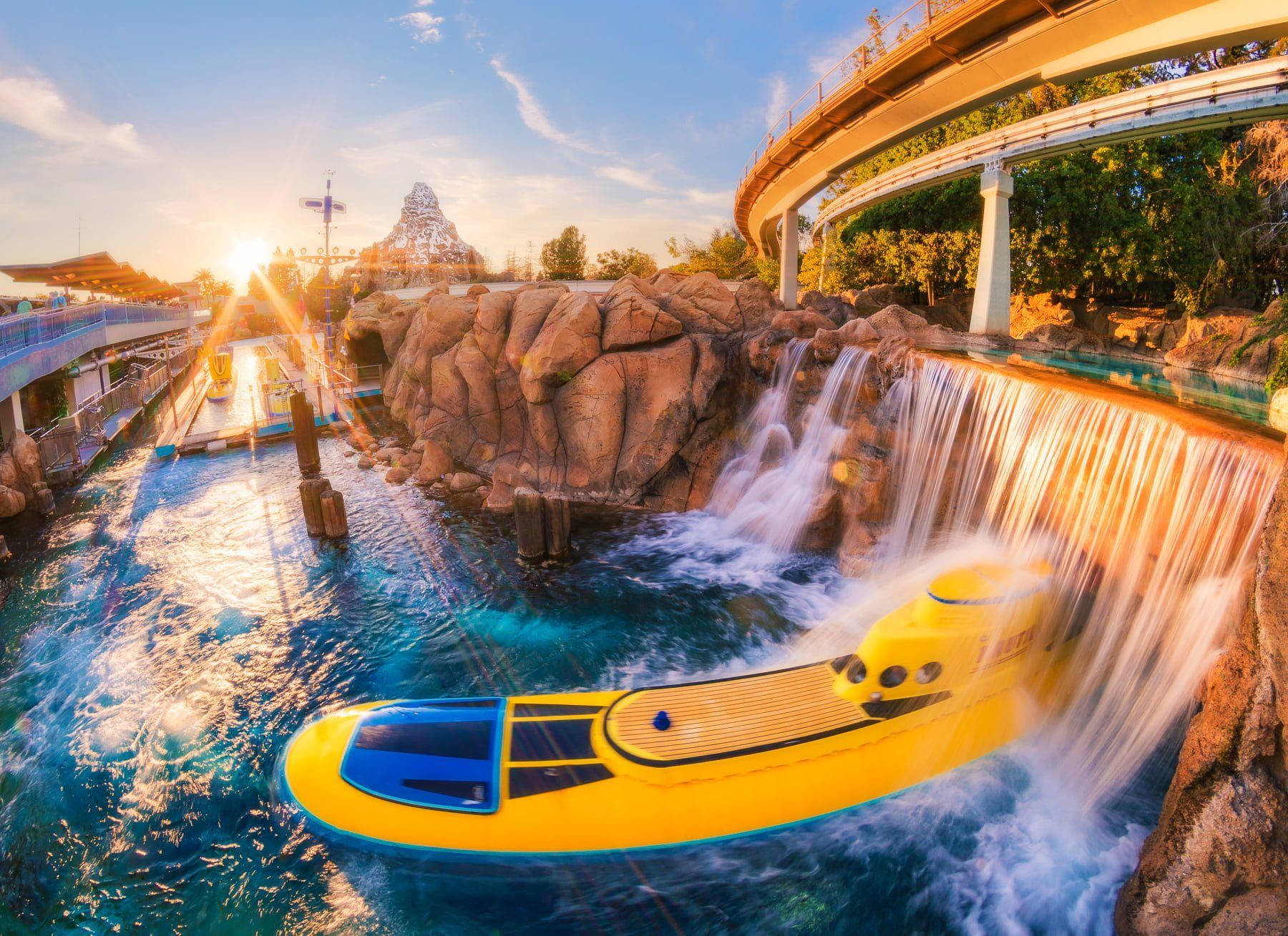 a yellow boat is floating in the water near a waterfall .
