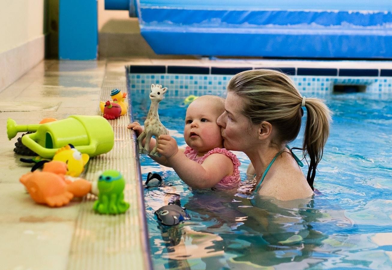 Mother and baby playing with toys in the pool