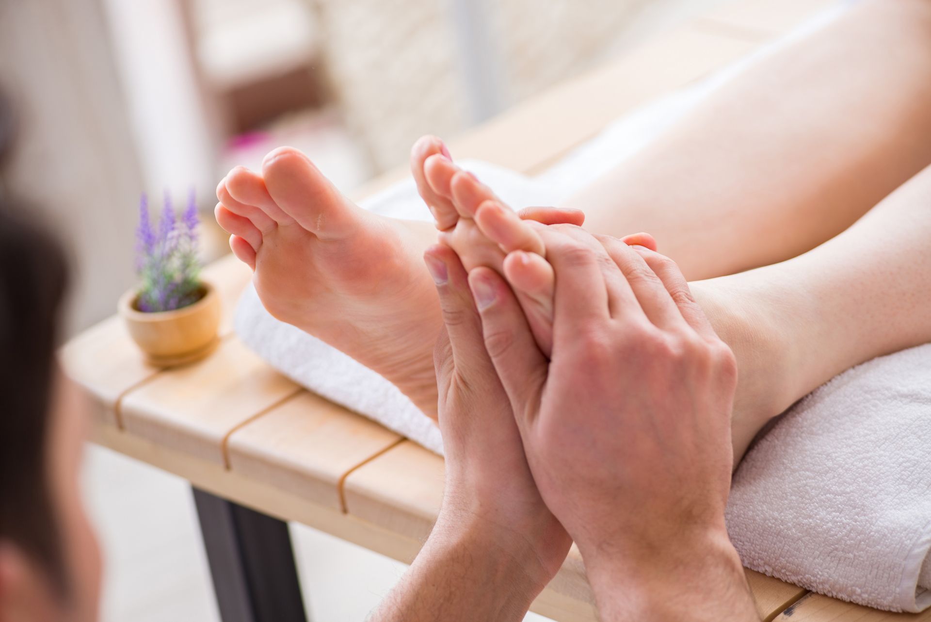 A person receives a relaxing foot massage in a spa setting, with hands gently pressing on the sole of the foot.