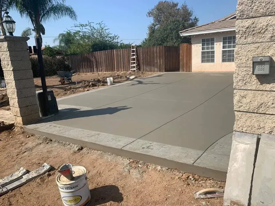 A concrete driveway is being built in front of a house.