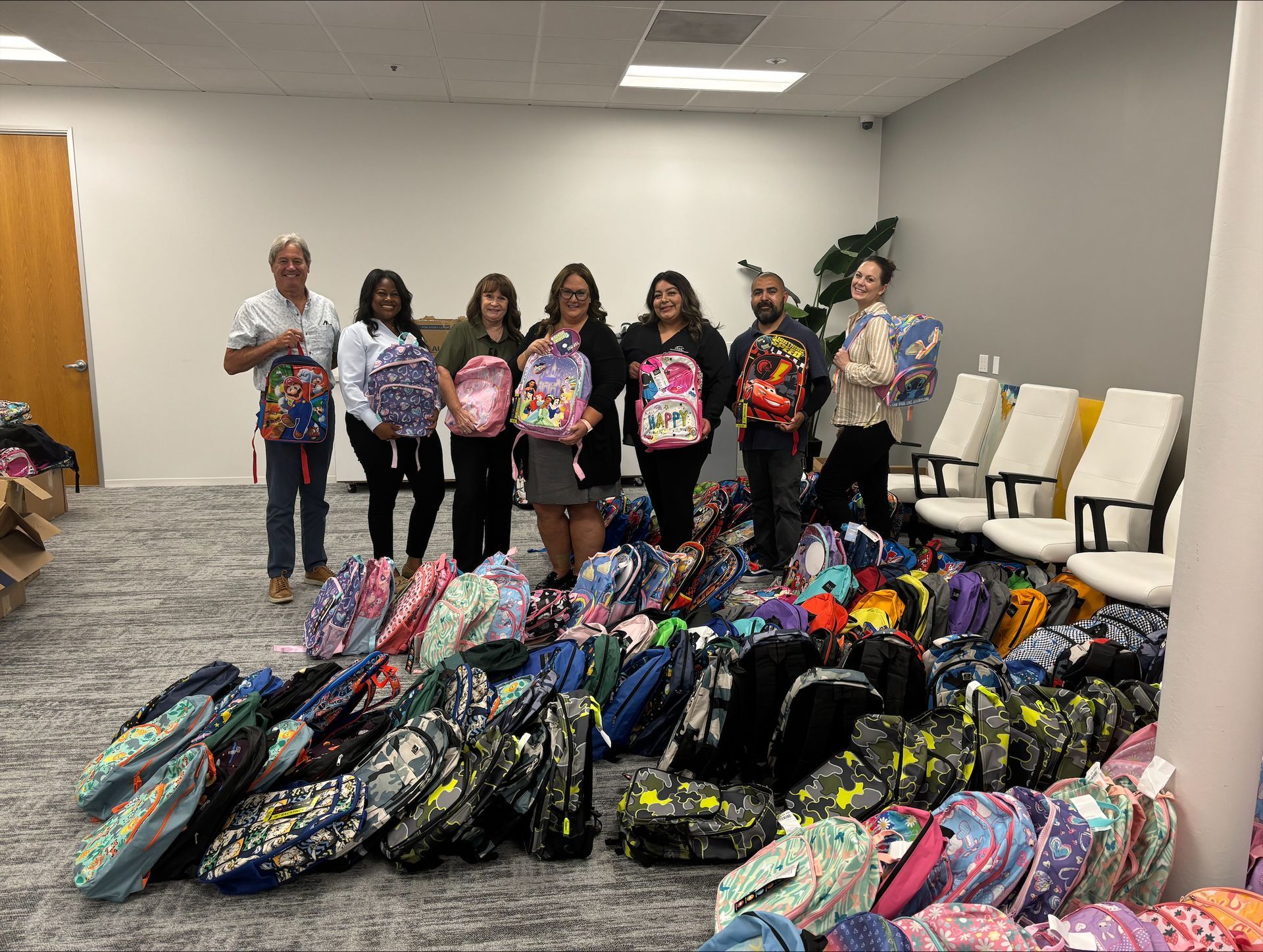 AMC Employees holding backpack donations for the Annual Backpack Drive 