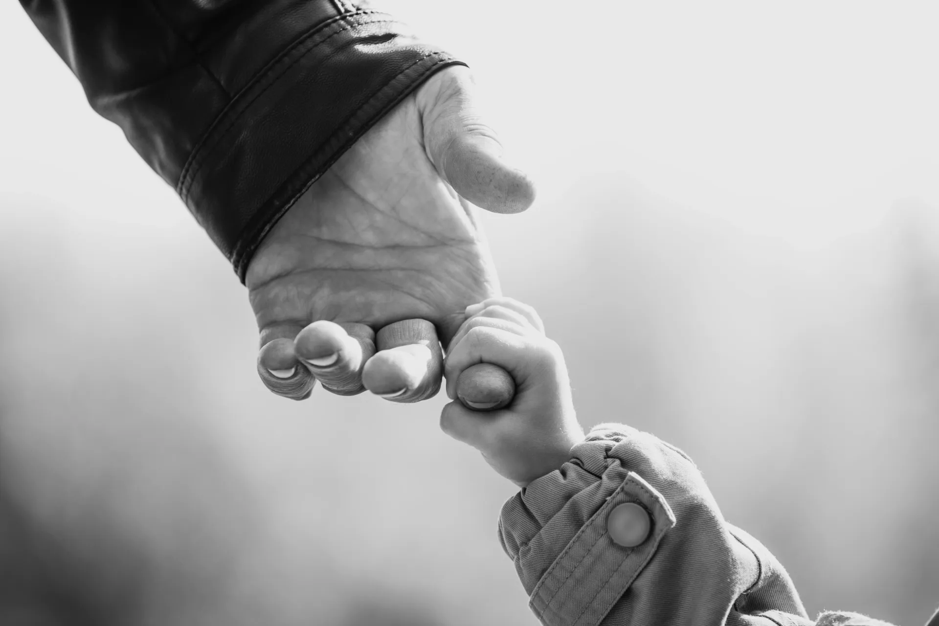 a black and white photo of a person holding a child 's hand .