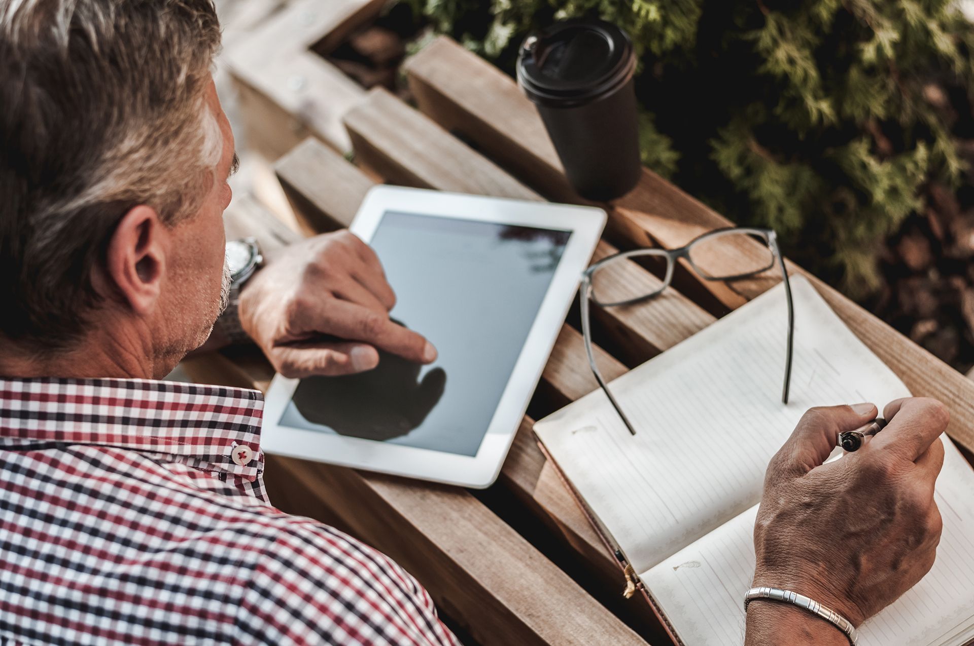 a man is using a tablet and writing in a notebook