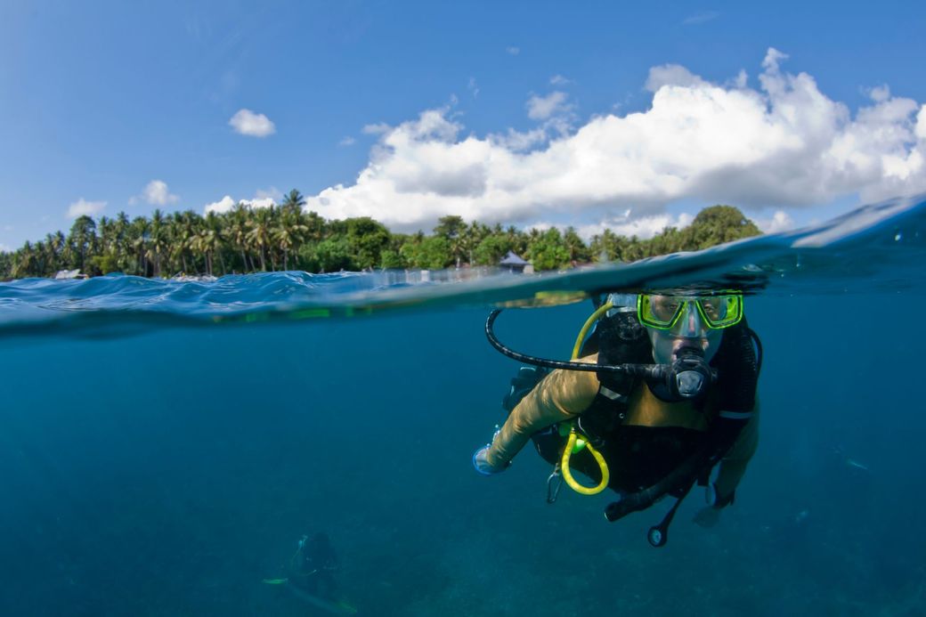 A scuba diver is swimming in the ocean near a small island.