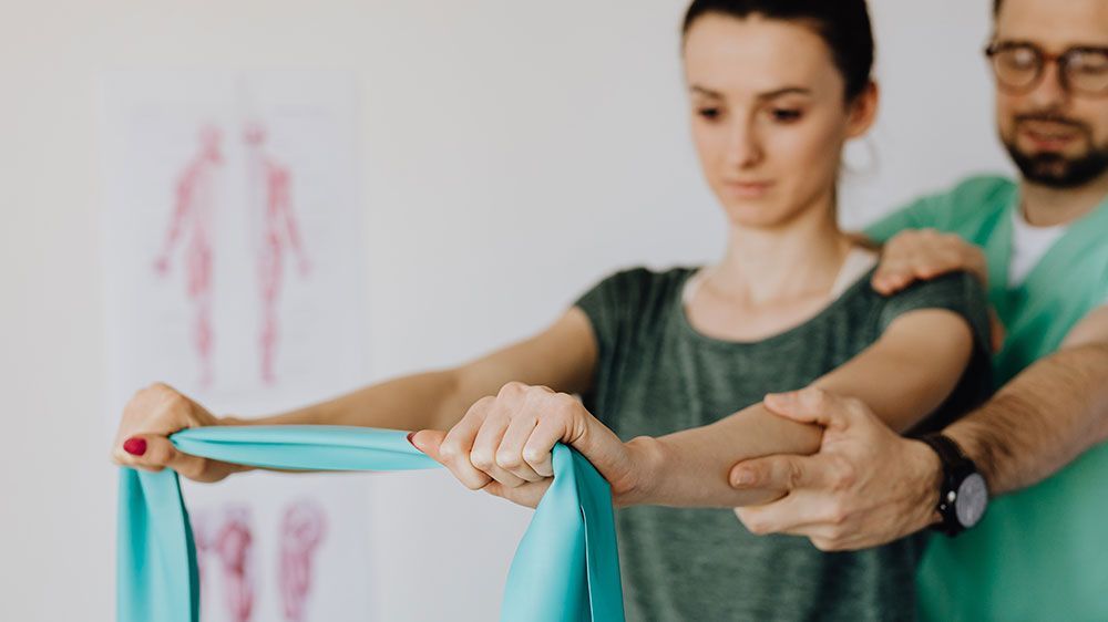 A man is helping a woman with a resistance band.