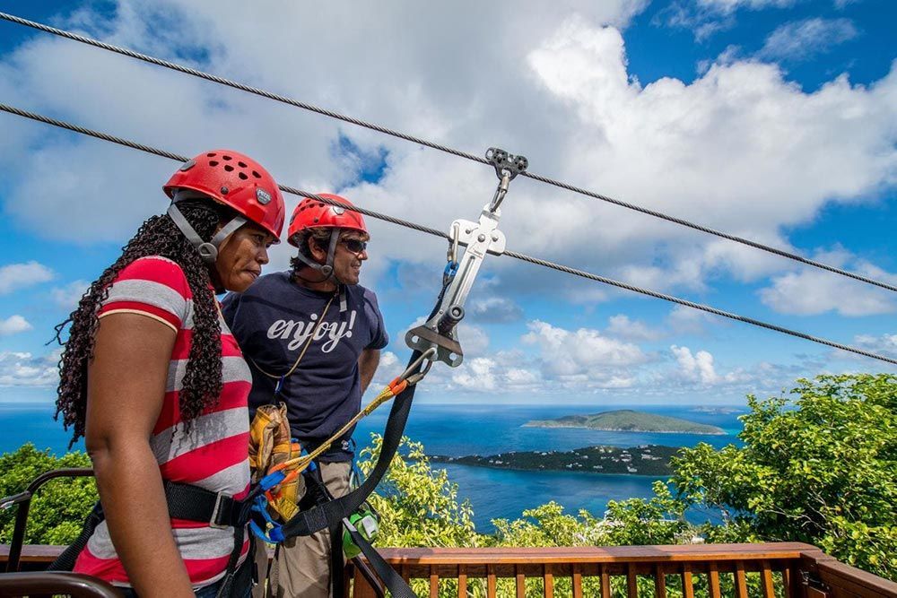 A man and a woman are riding a zip line over a body of water.