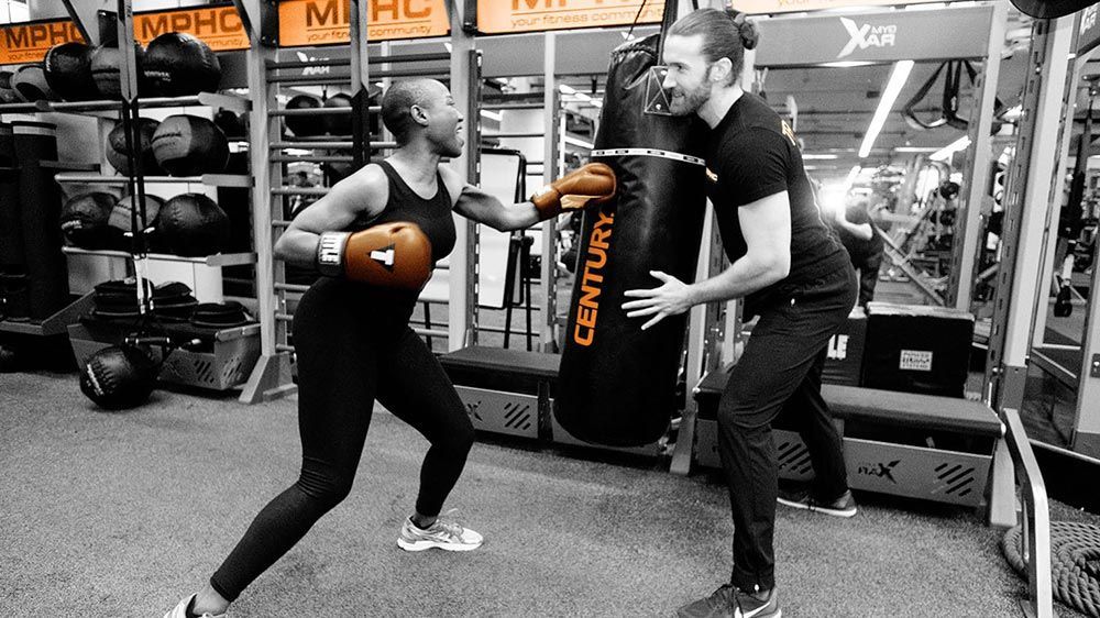 Woman Hitting Boxing Bag While Man Holds It