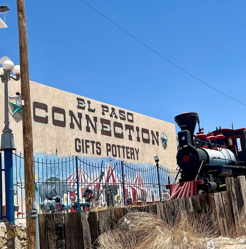 A train is parked in front of a el paso connection gifts pottery sign