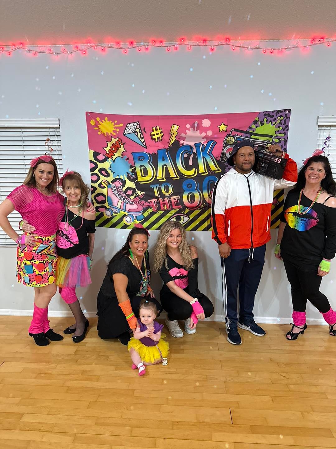 Group dressed in 80s attire poses in front of 