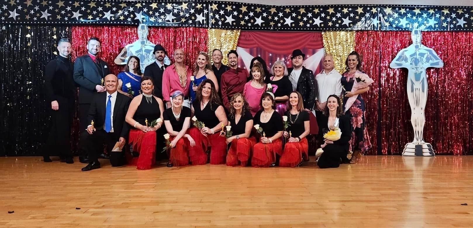 Group of people pose for photo at an awards event. They are on a wooden floor, with a star-themed backdrop.