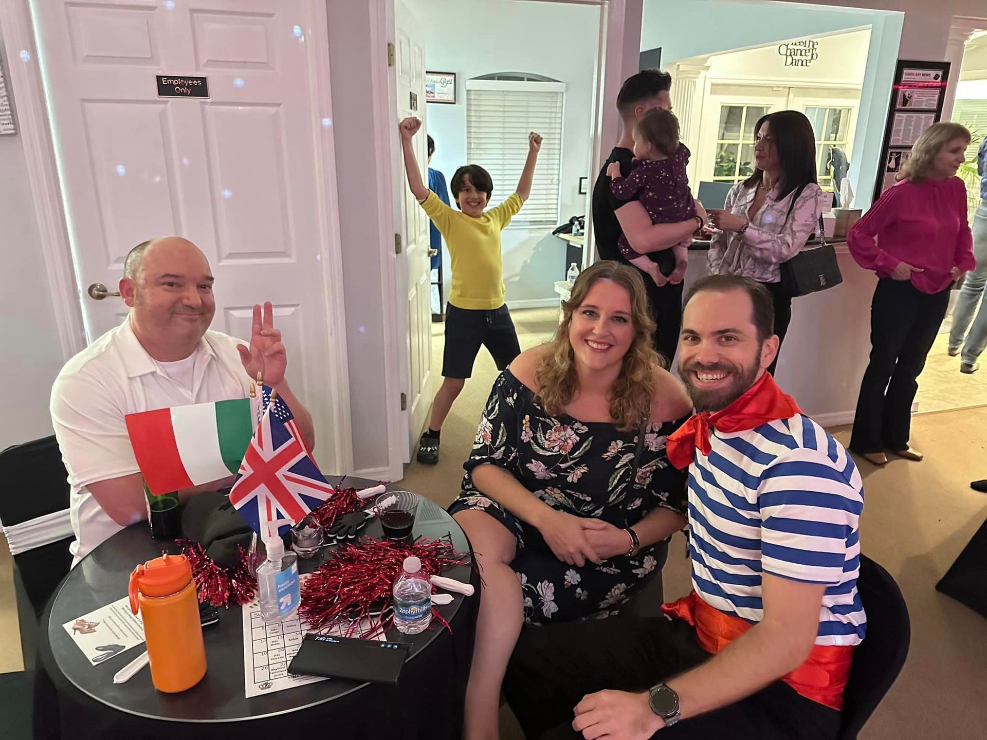 People celebrating, some with flags, in a room with a disco ball; a boy cheers in the background.
