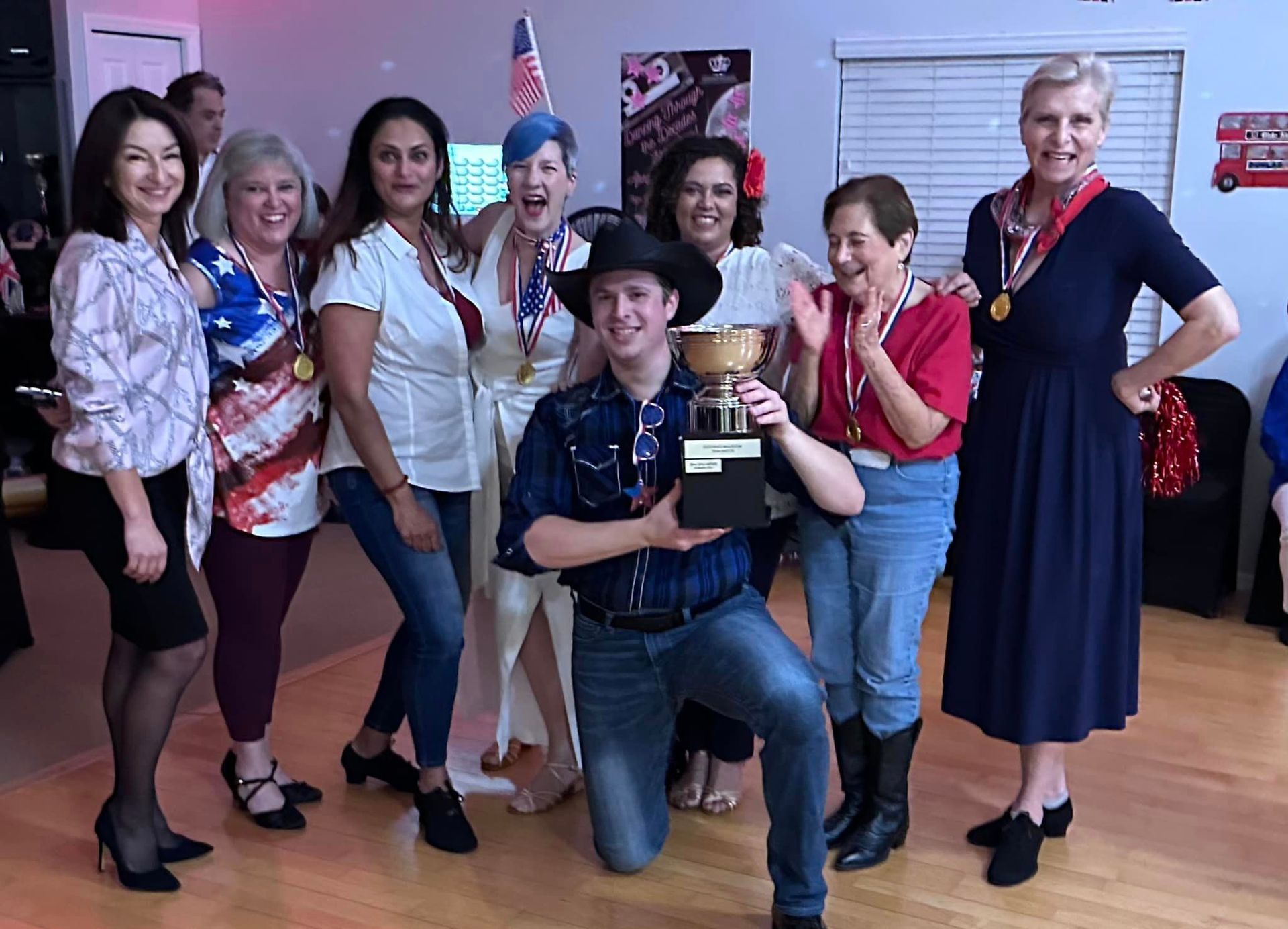 Group of people smiling, holding a trophy, patriotic theme, party setting.