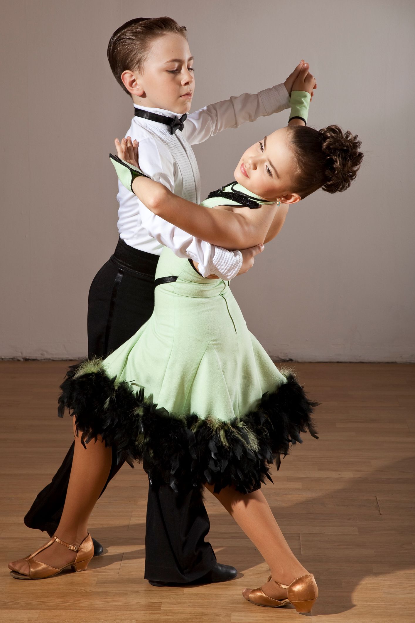 Boy and girl in formal attire ballroom dancing. Girl in green dress, boy in white shirt and bow tie.