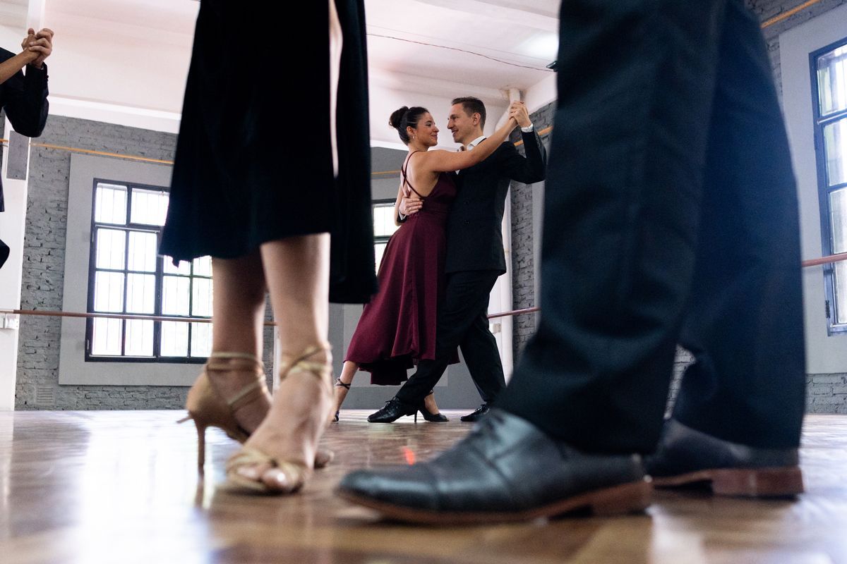 A couple dances the tango during a professional ballroom dance lesson in a studio setting.