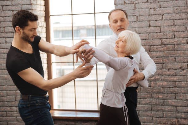 A dance instructor teaching a couple at the ballroom.