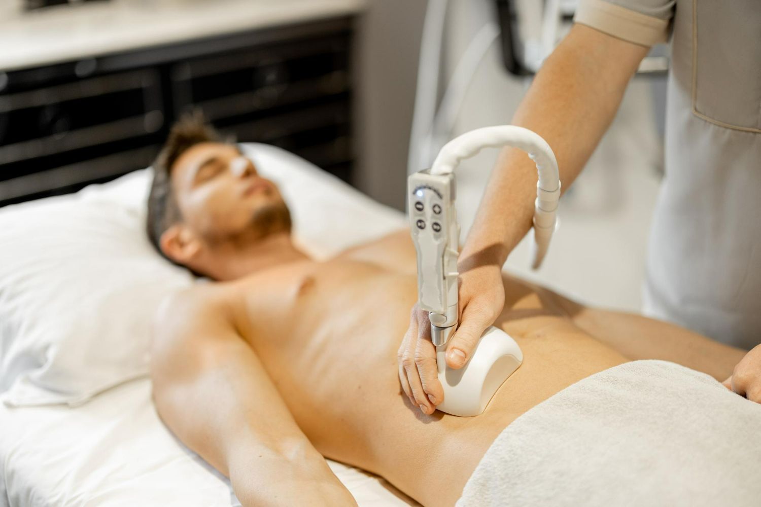 Man receiving abdomen treatment with a handheld device at a medical spa.