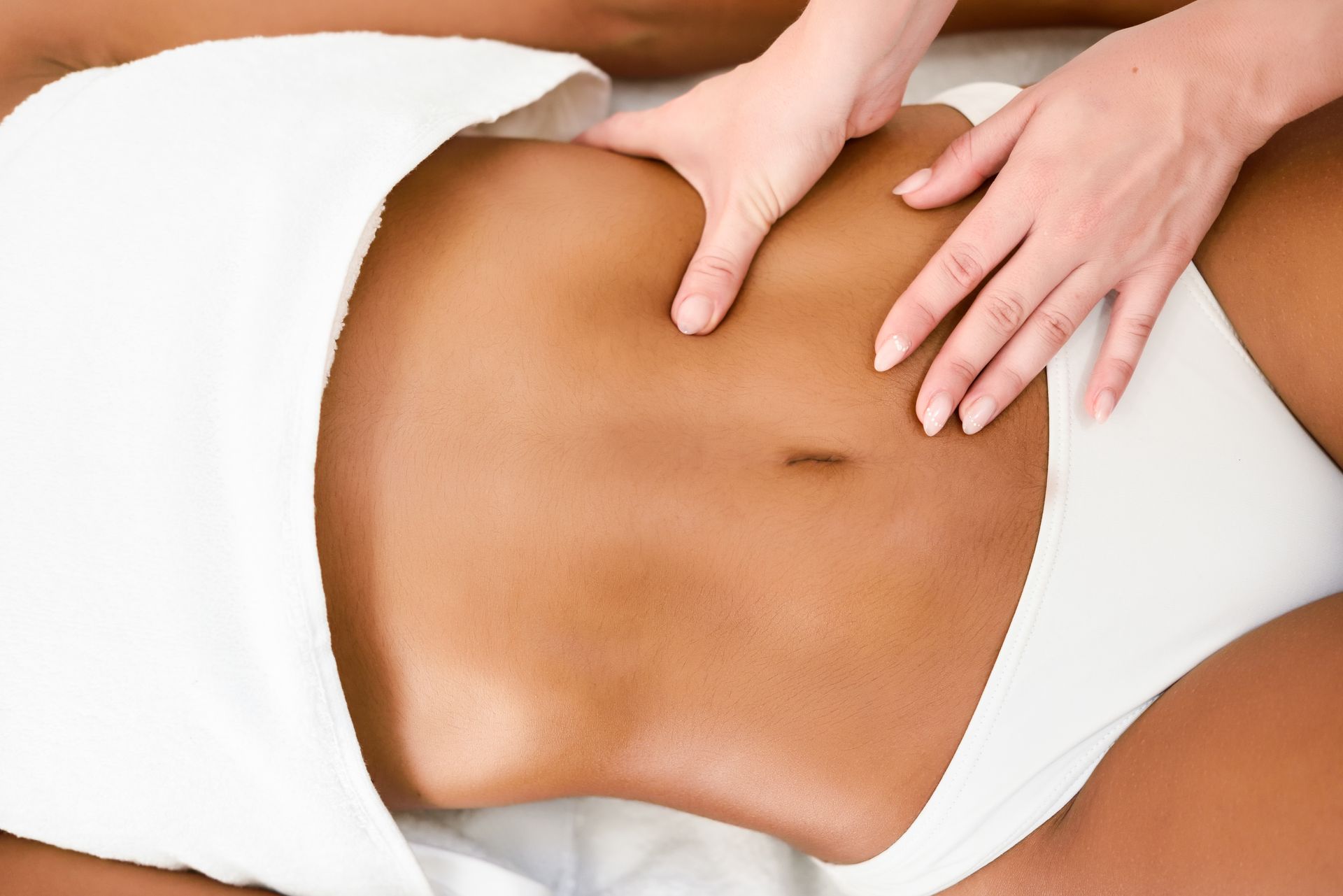 A woman is getting checked for fat on her stomach area.