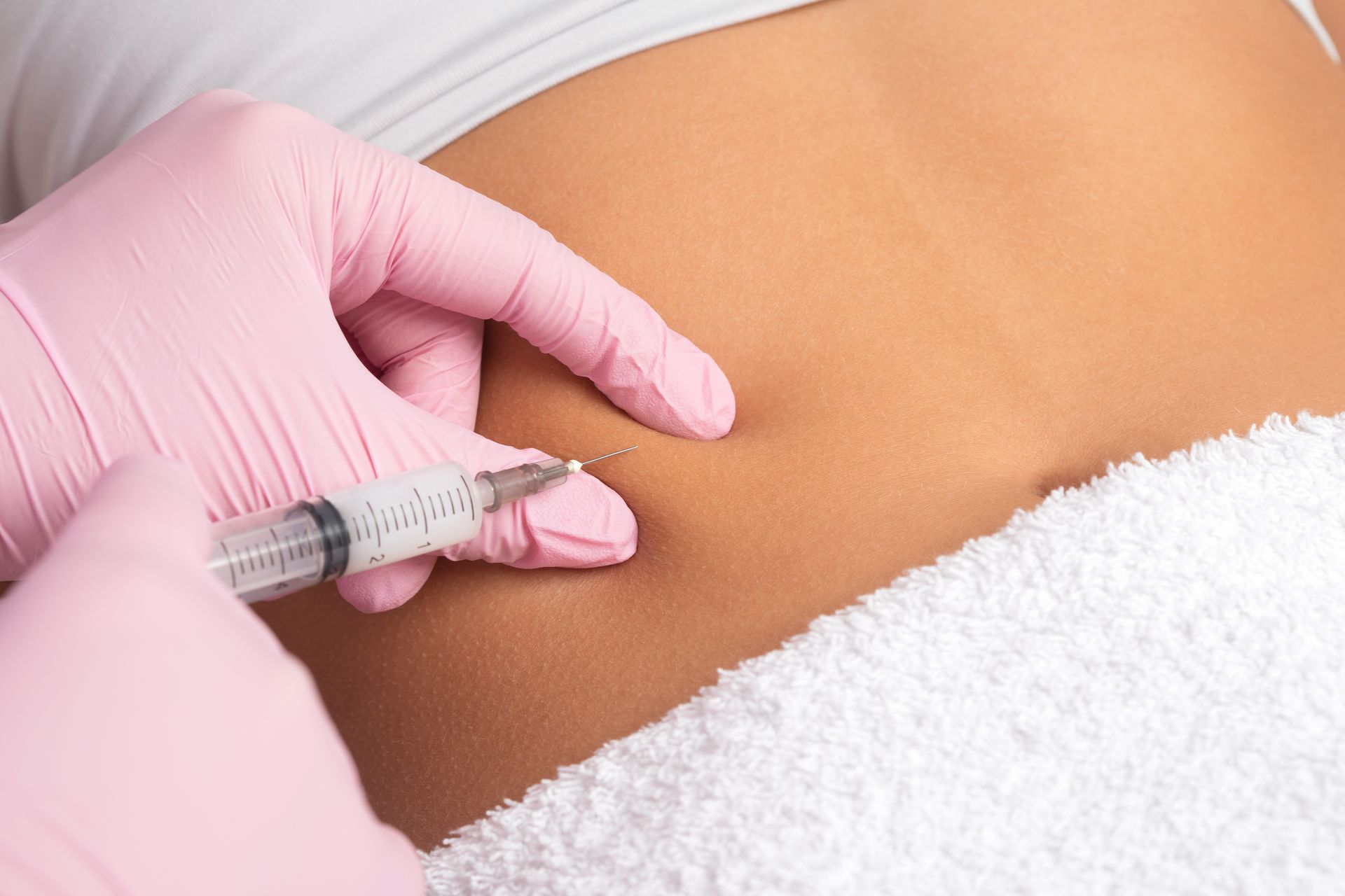 A woman is getting an injection in her stomach.