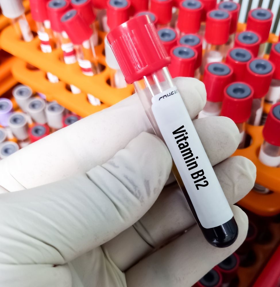 A hand is holding a test tube of vitamin b12