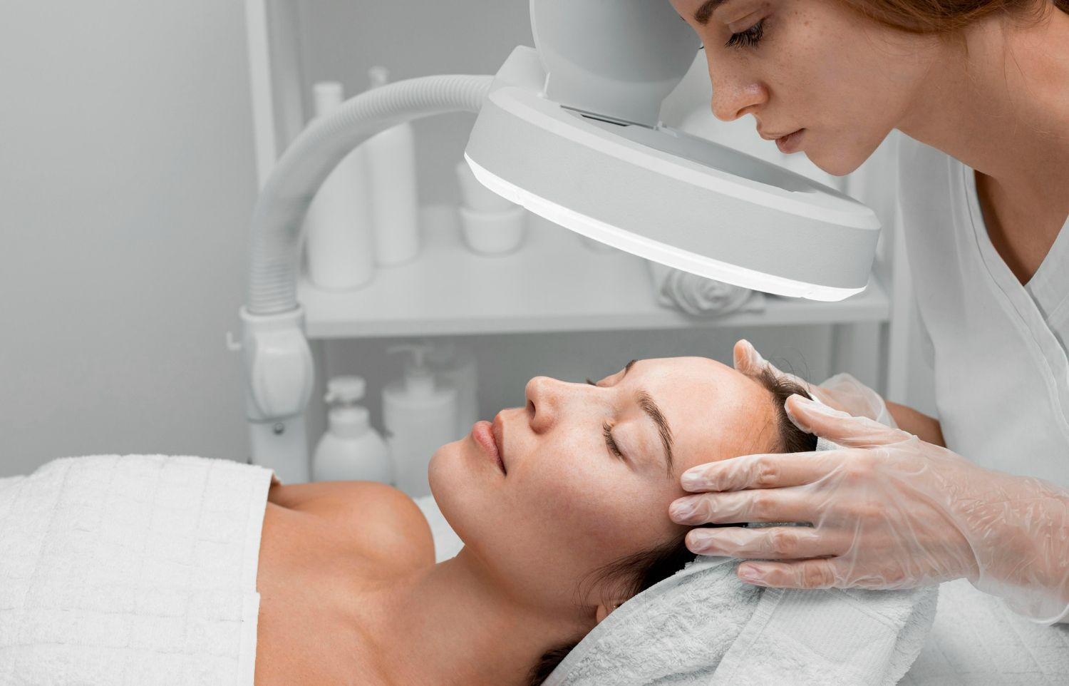 Woman undergoing facial skin examination under bright light.