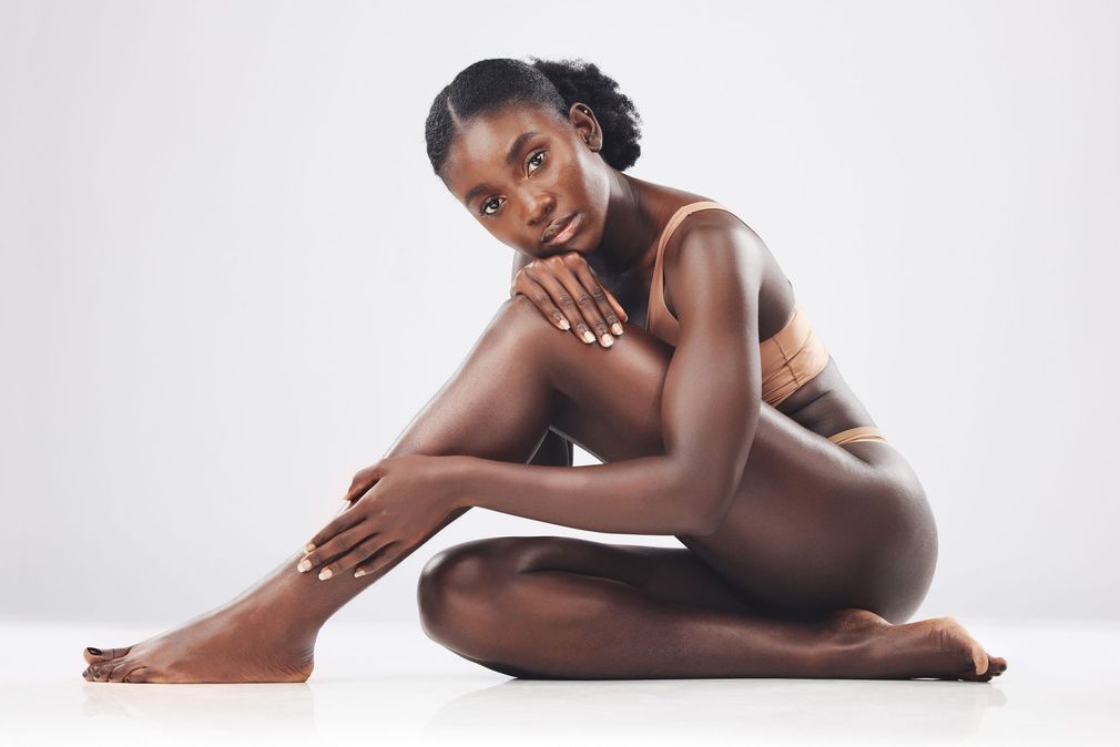 Three women in underwear are hugging each other on a brown background.