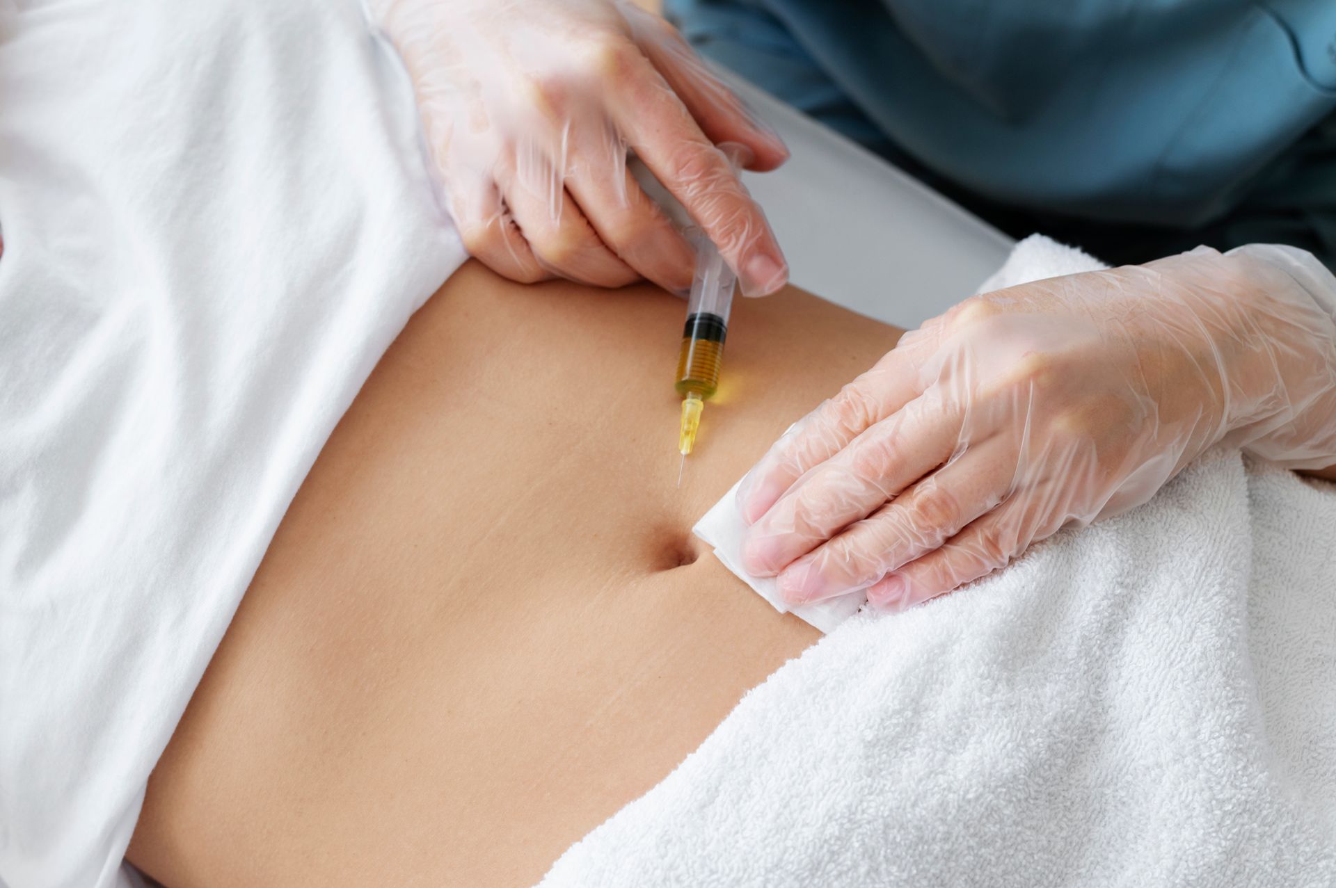 A woman is getting an injection in her stomach.