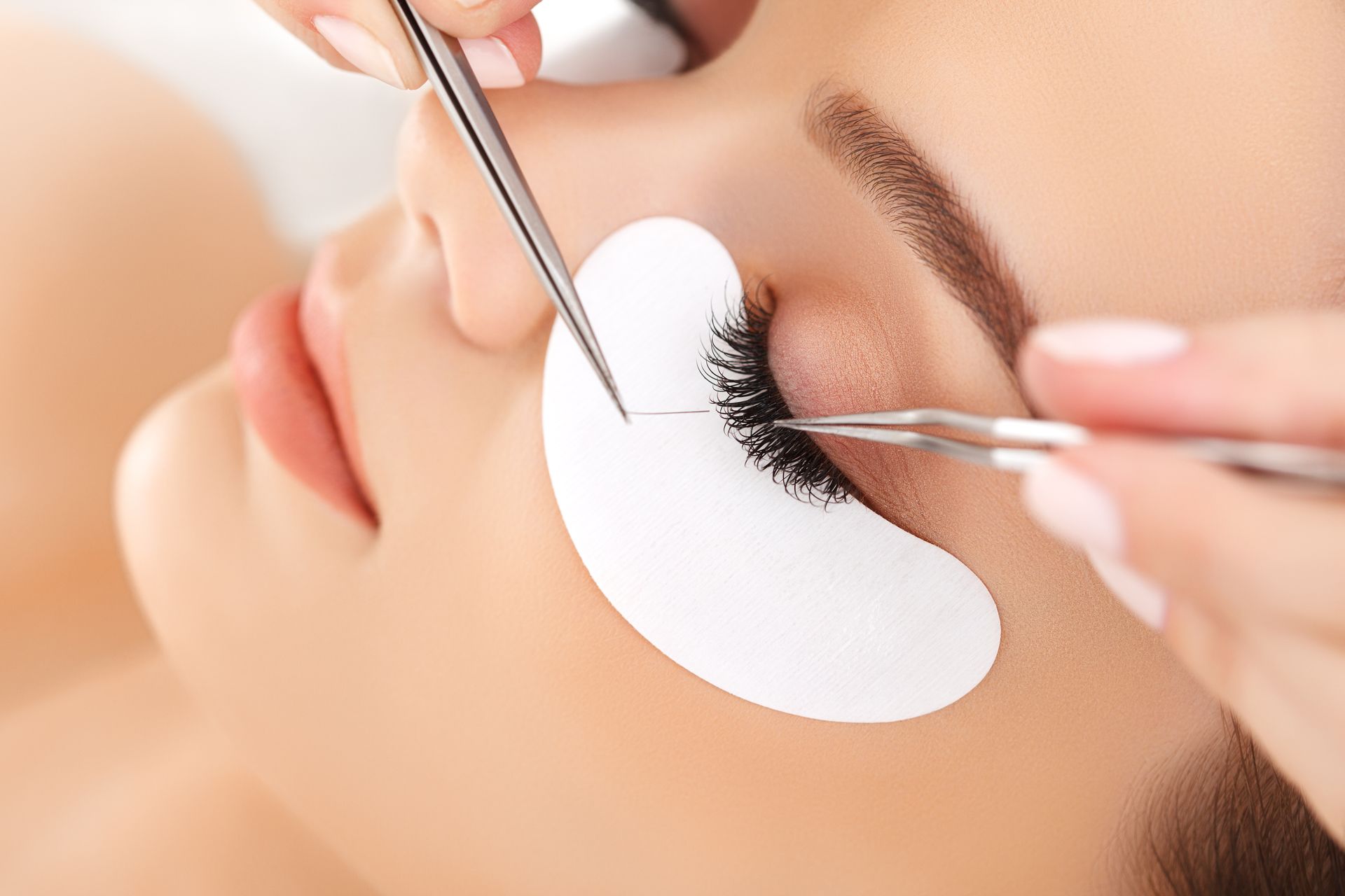 A woman is getting eyelash extensions in a beauty salon.