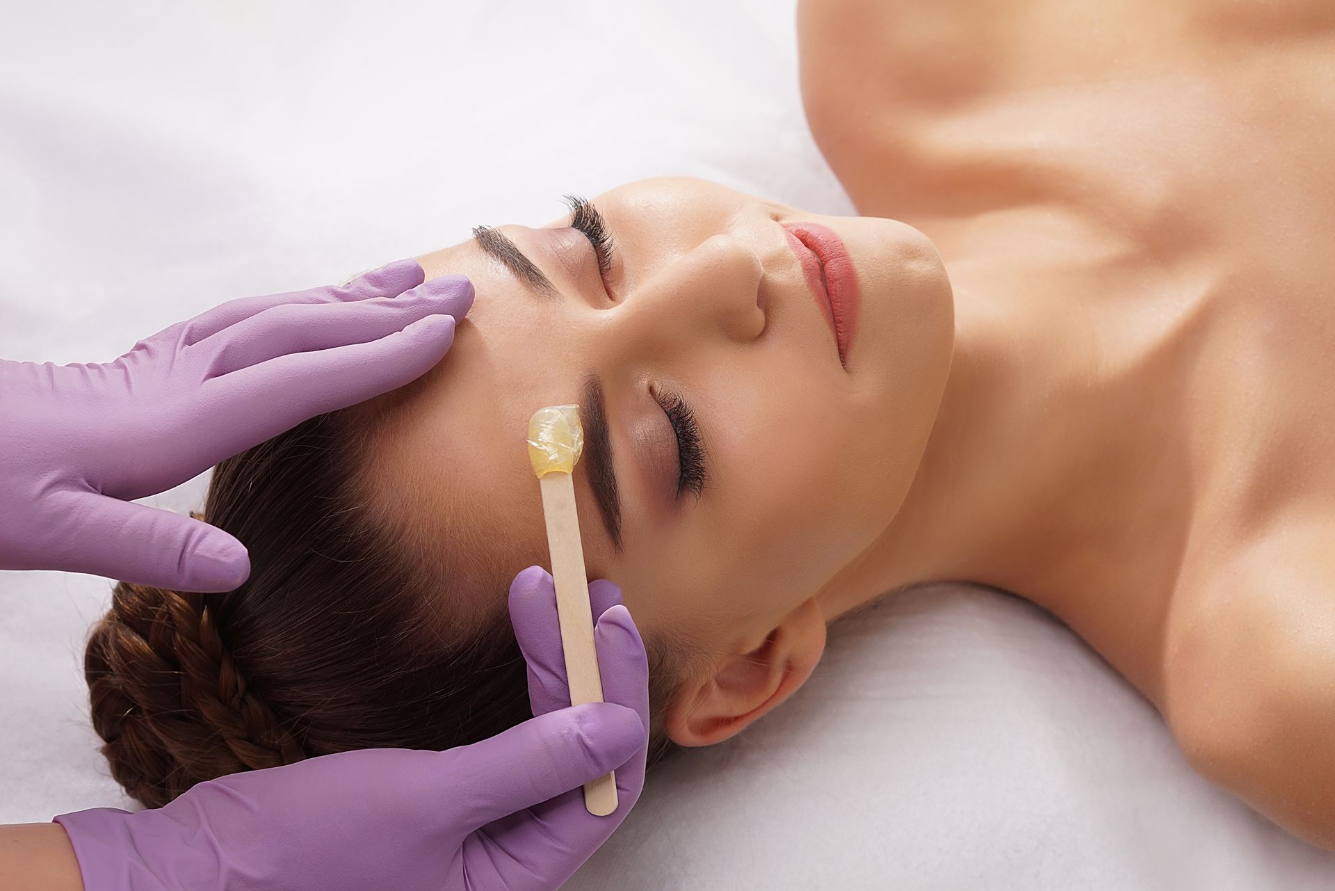 A woman is getting her eyebrows waxed in a beauty salon.