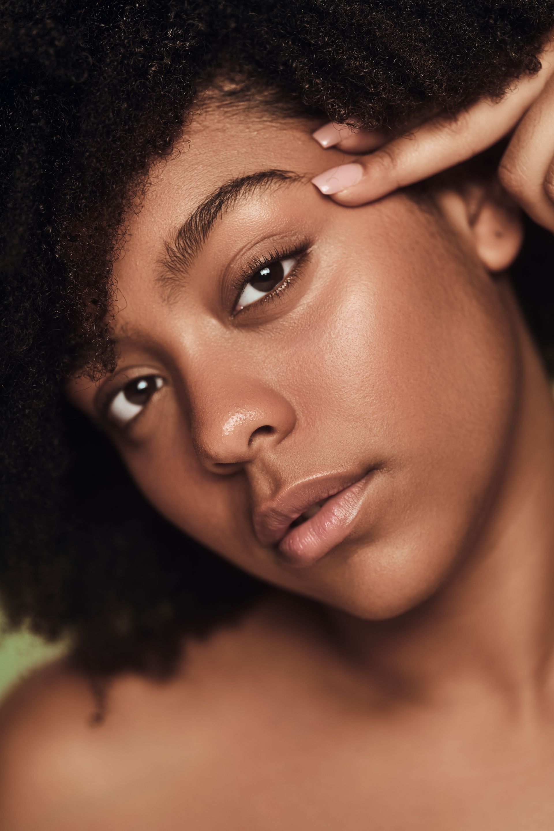 A close up of a woman 's face with her hand on her eyebrow.