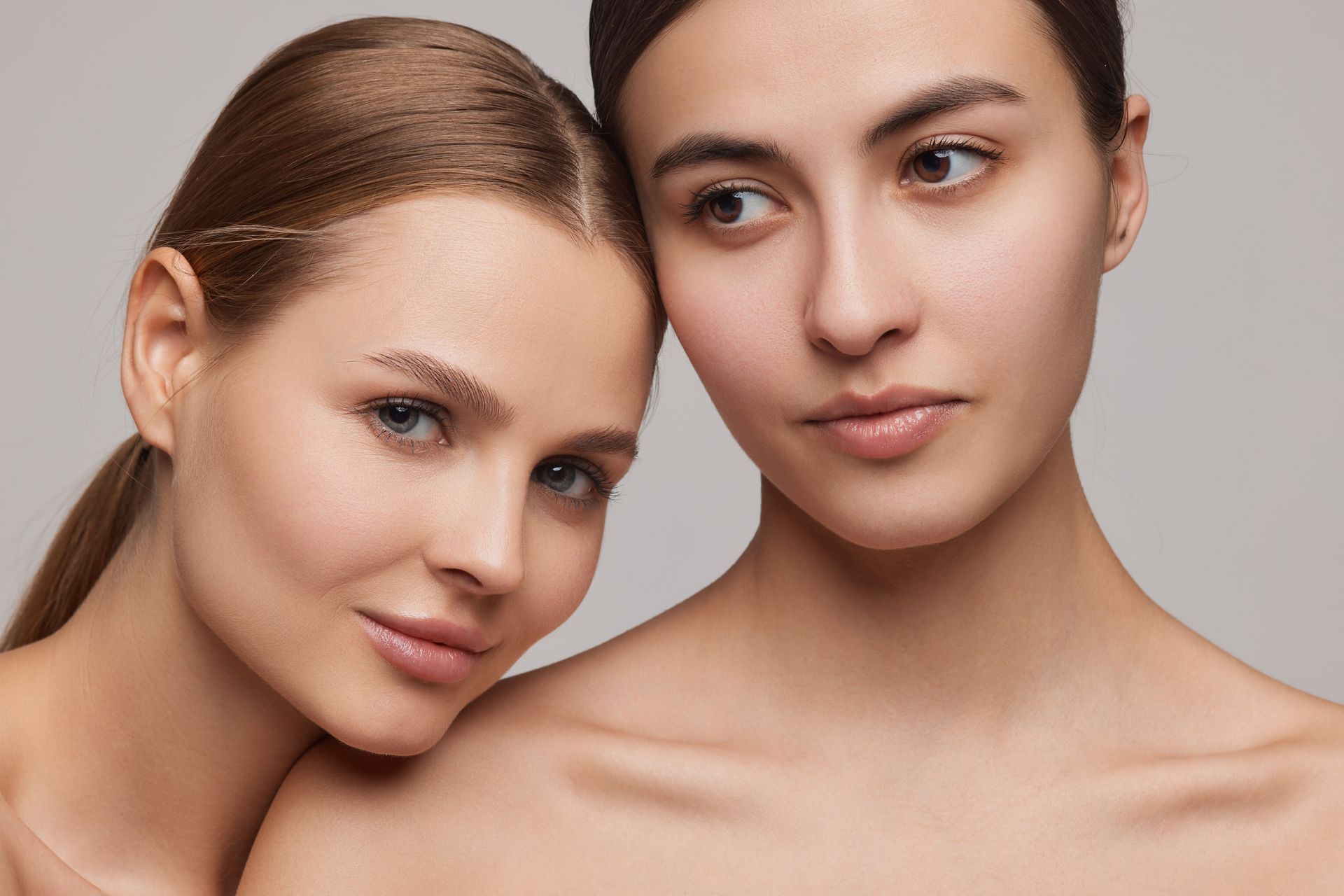 Two women are hugging each other and looking at the camera.