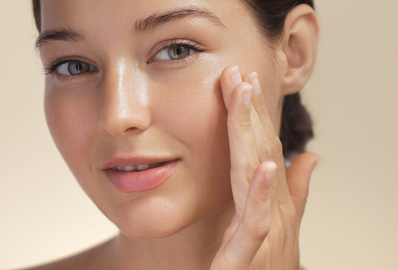 A close up of a woman applying cream to her face.