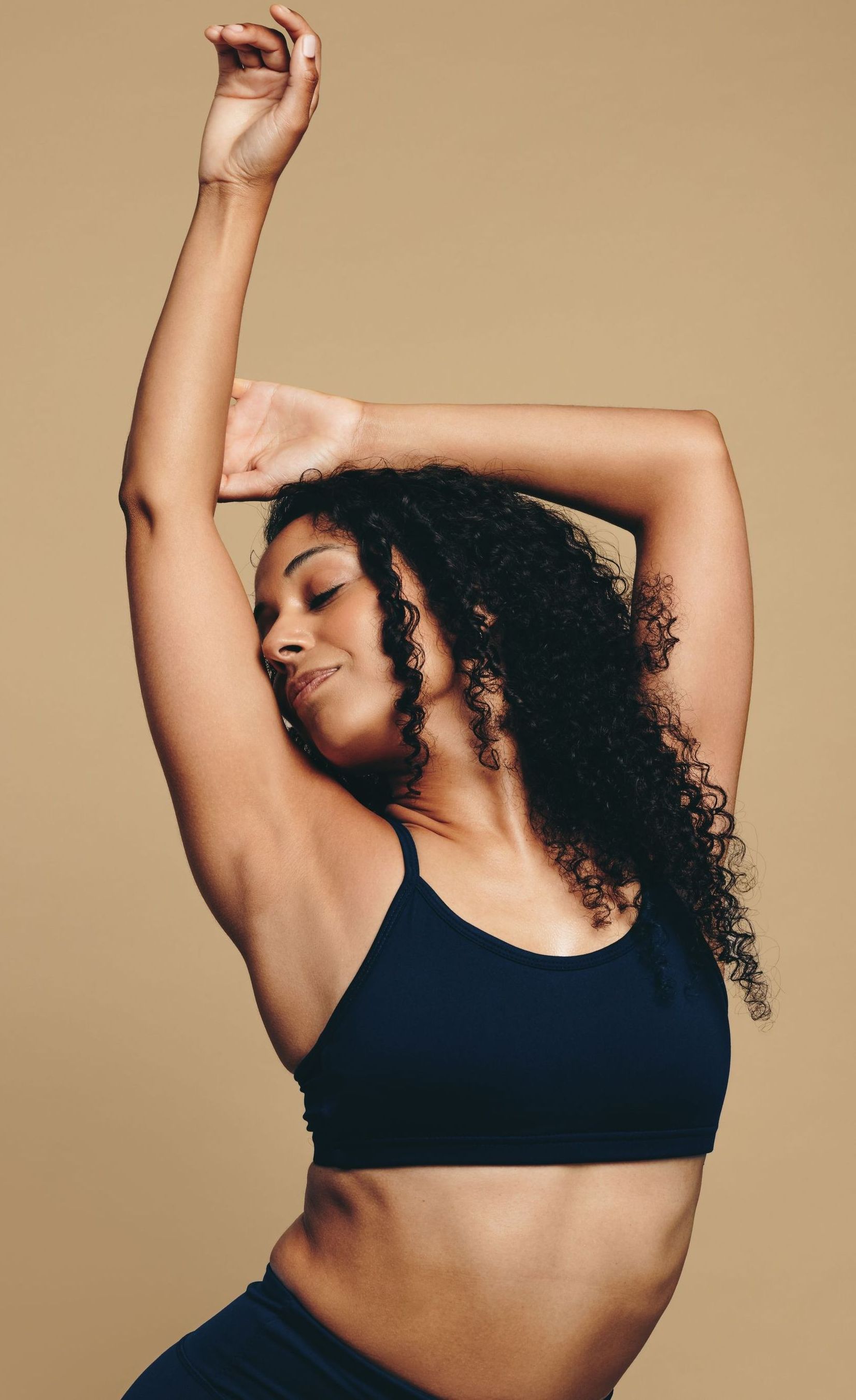 A woman with curly hair is dancing with her arms in the air.