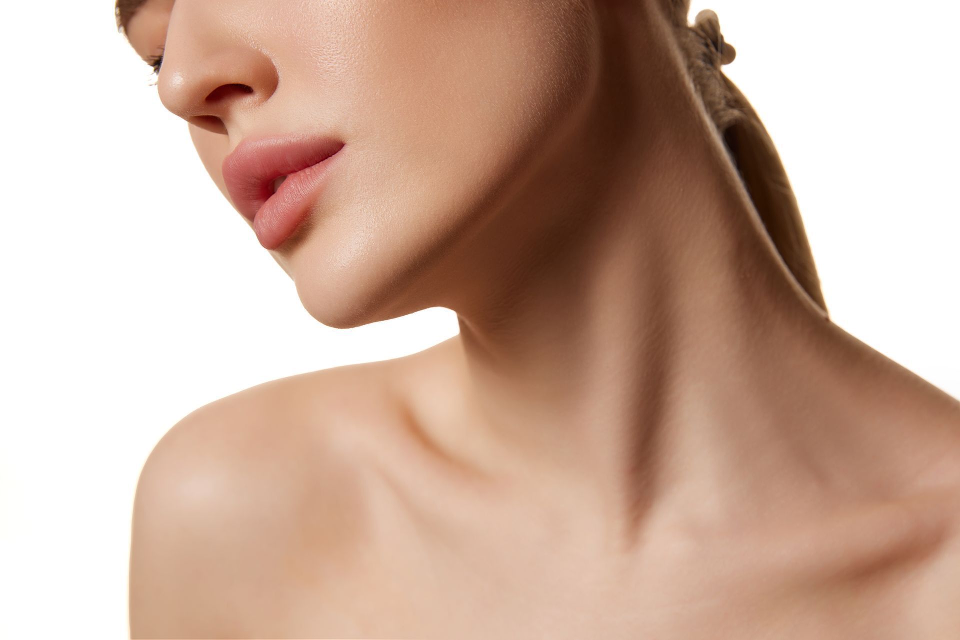 Woman's face and neck, tilted down, smooth skin, light complexion, neutral background.