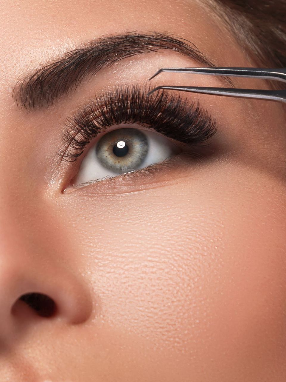 A woman is getting her eyebrows done with tweezers.