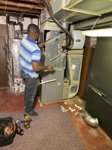 Man inspecting a damaged furnace in a basement, with debris and exposed pipes nearby.