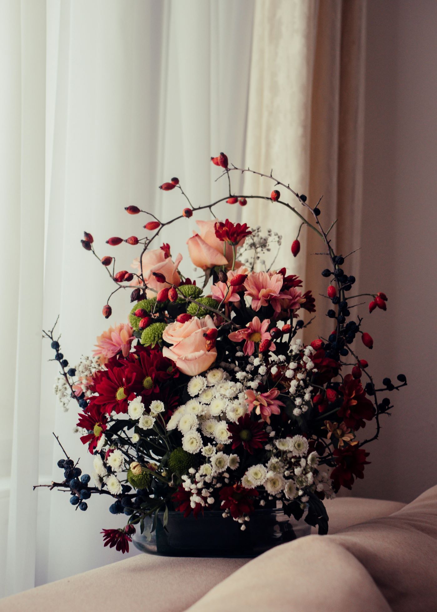 A bouquet of flowers is sitting on a table in front of a window.