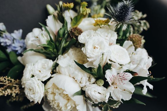 A close up of a bouquet of white flowers on a black surface.