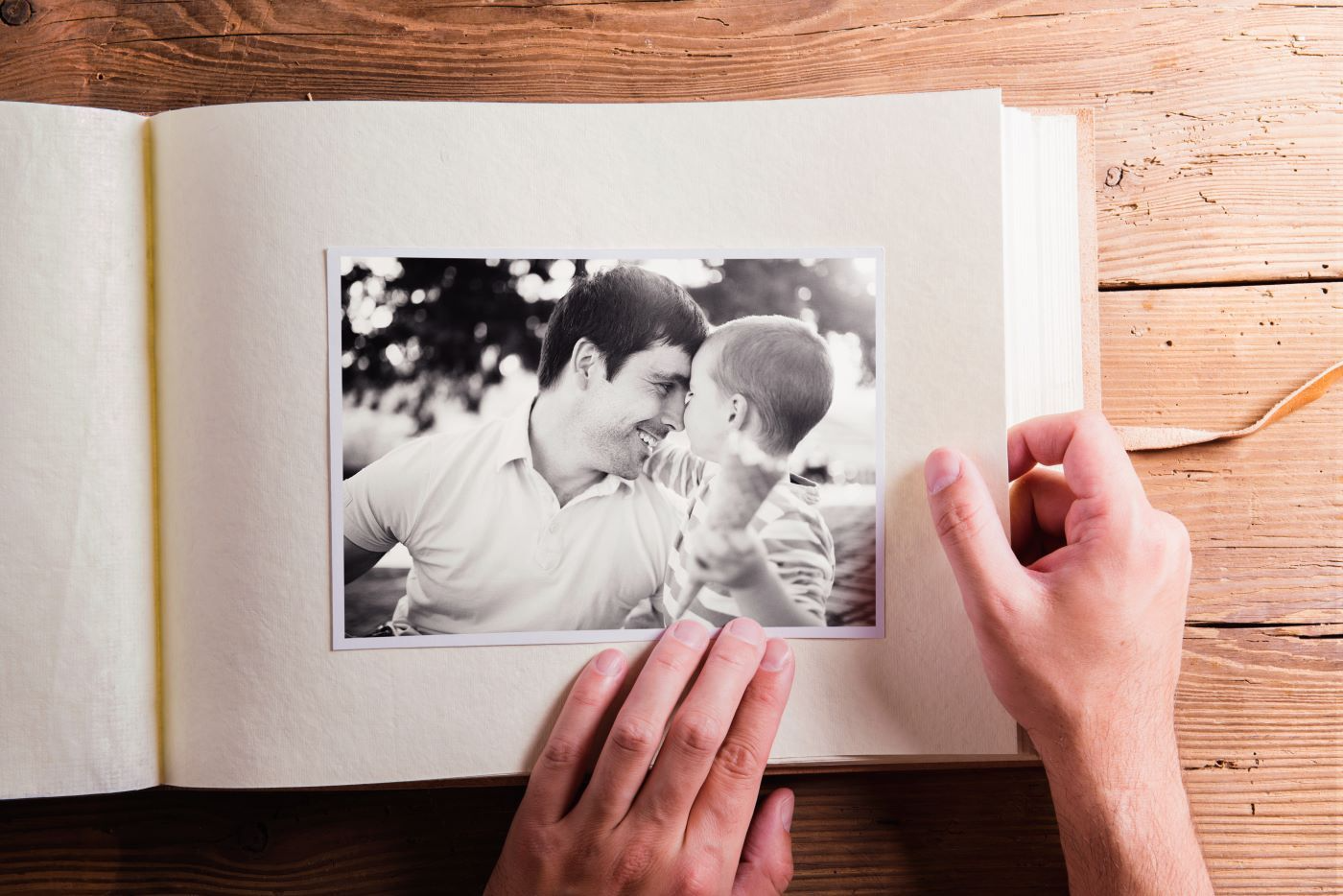 A person is holding a picture of a man and a boy in a photo album.