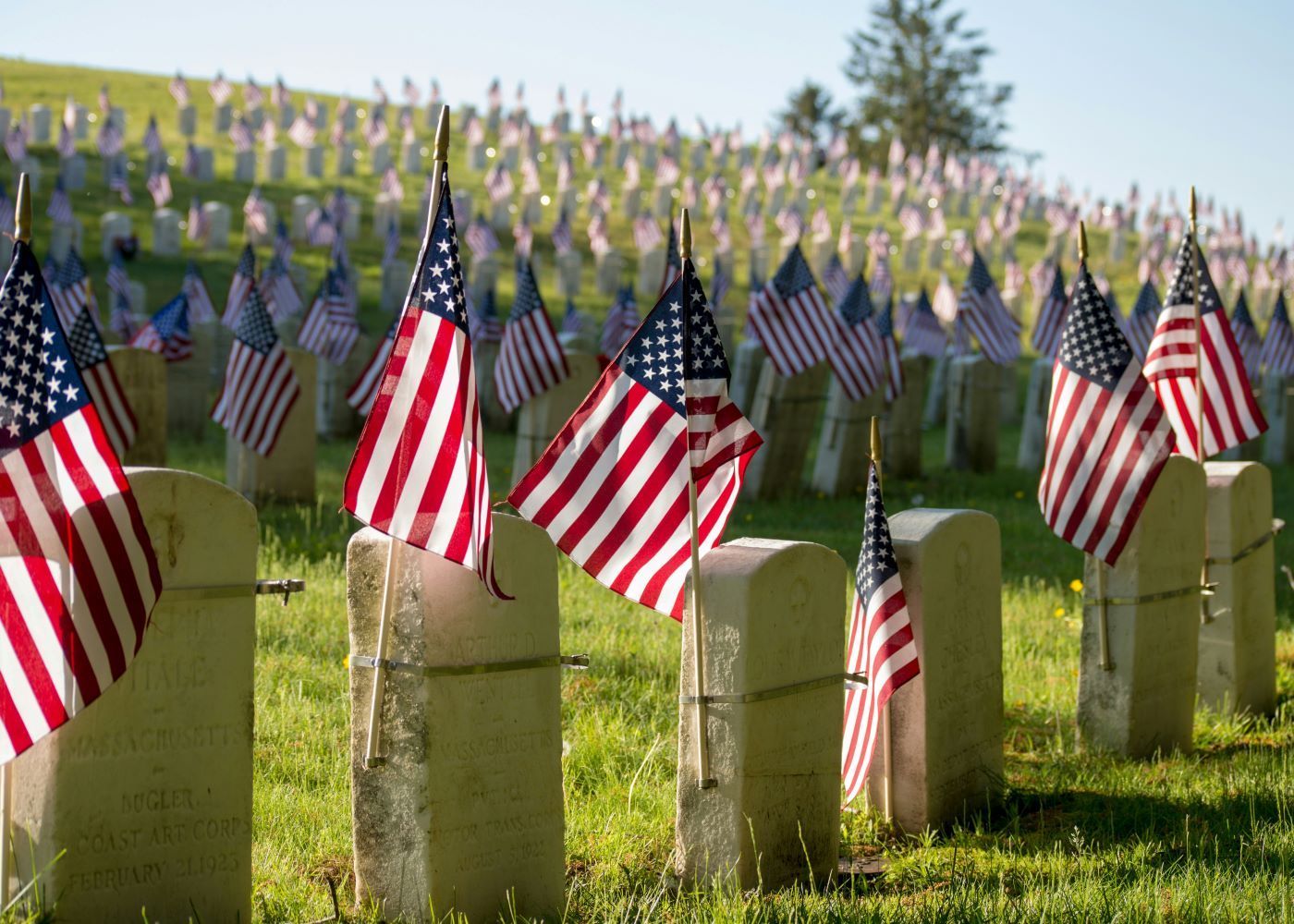 A cemetery filled with graves and american flags.