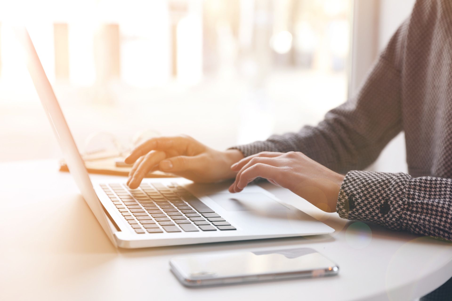 A person is typing on a laptop computer at a desk.