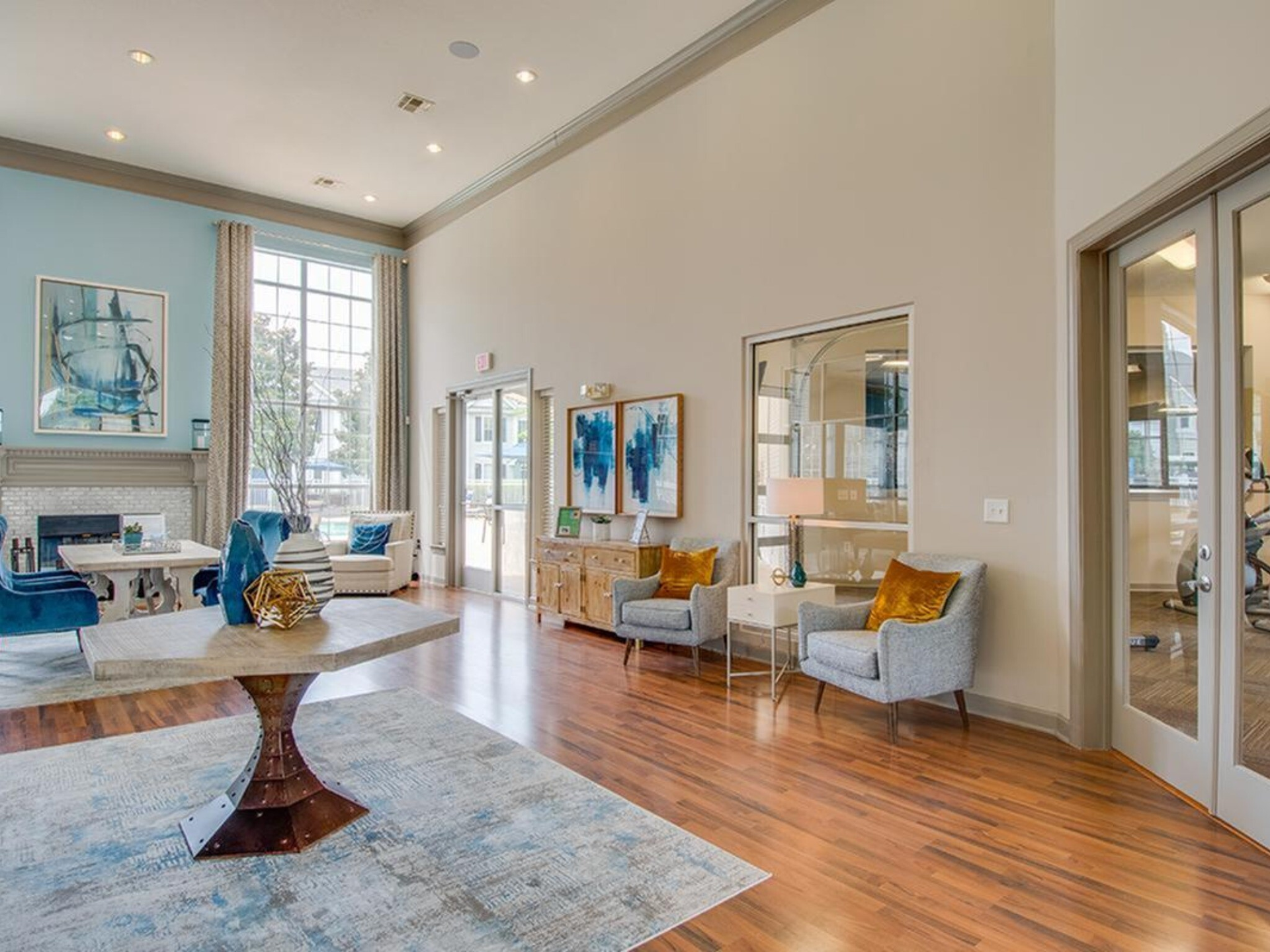Lobby with high ceilings and hardwood floors. Light blue and beige color scheme. Two seating areas and artwork are visible at Scout Landing.