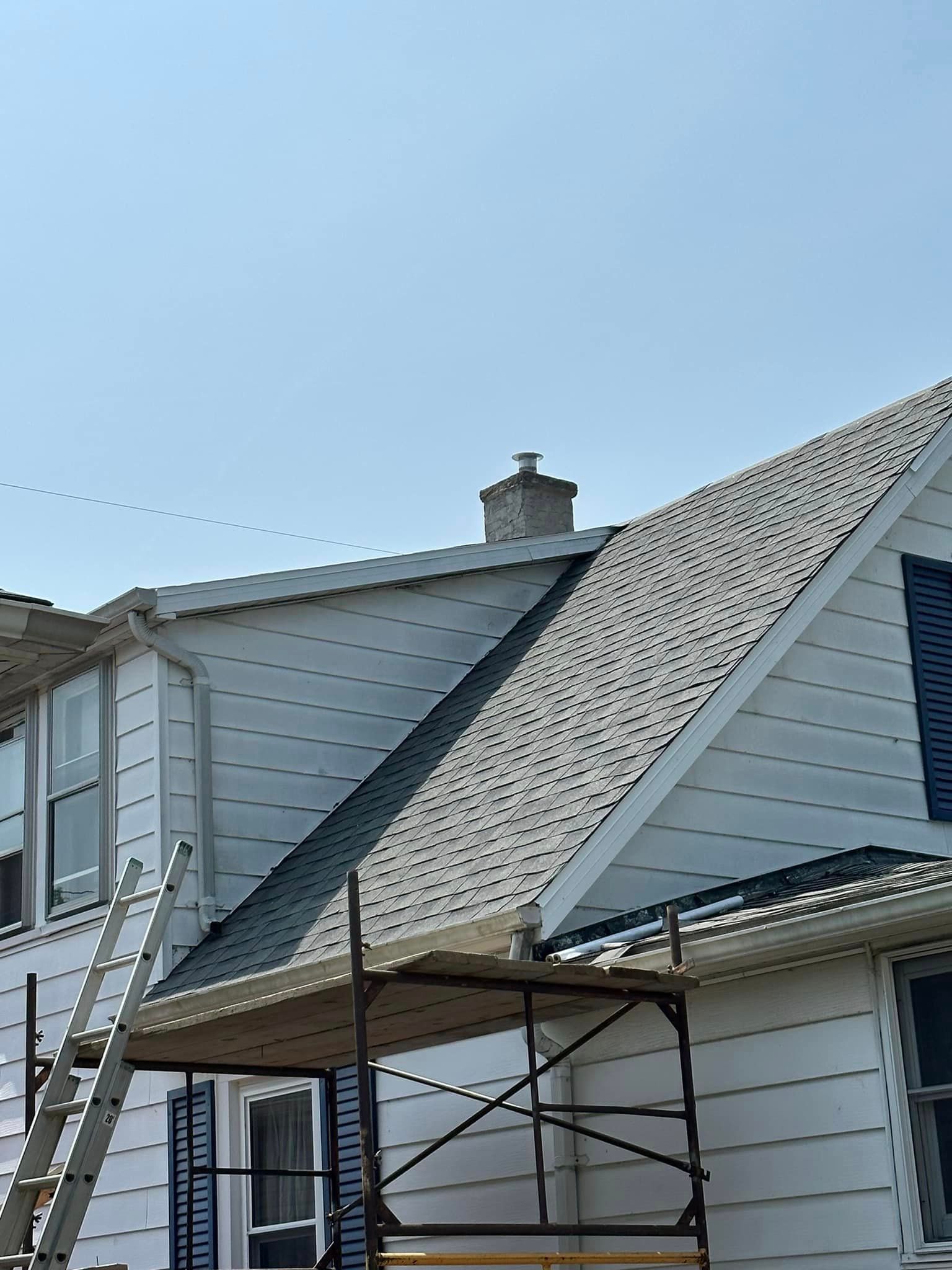 A House With A Chimney On The Roof And A Ladder On The Side Of It - Sandusky, OH - Petrick Roofing and Remodel LLC