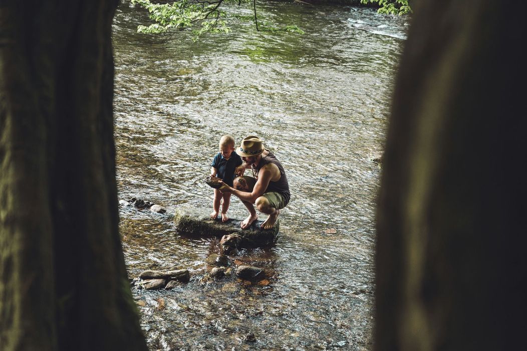 A man and a child are kneeling in a river.