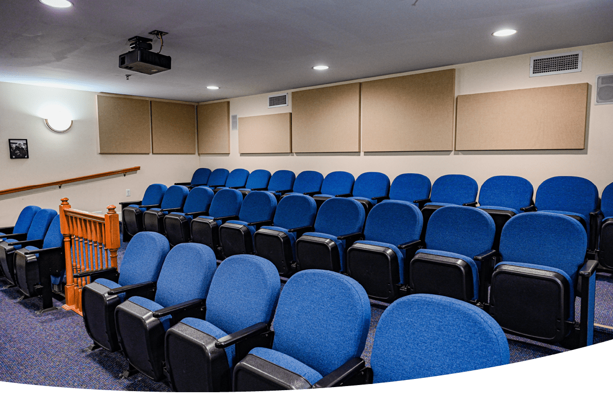 an auditorium with blue chairs and a projector on the ceiling