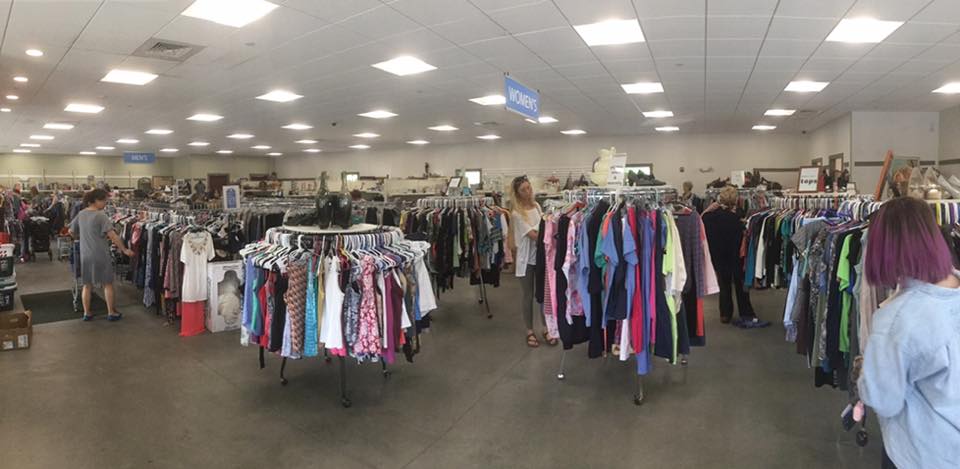 A woman with purple hair is shopping in a thrift store.