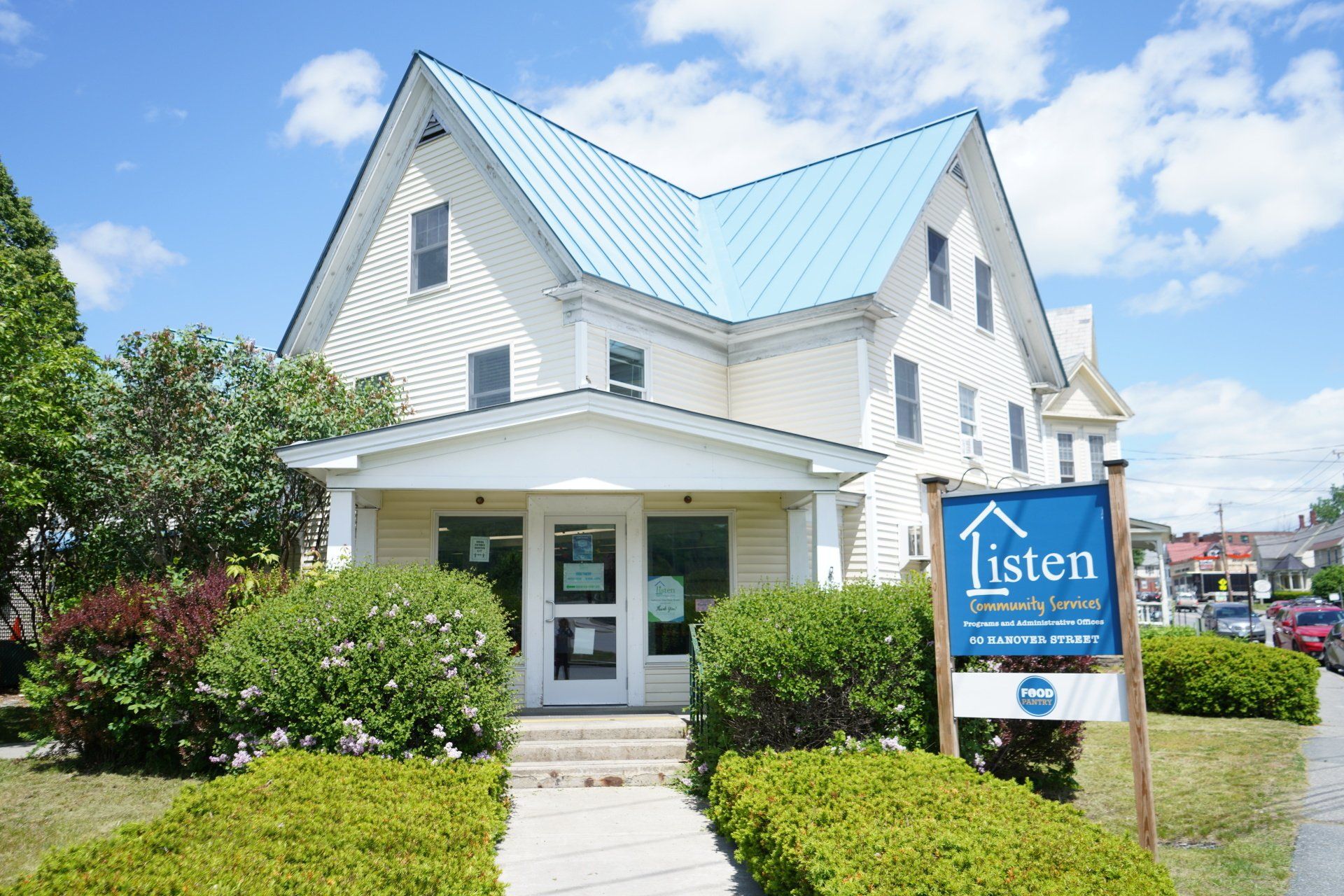 A white house with a blue roof and a sign that says listen