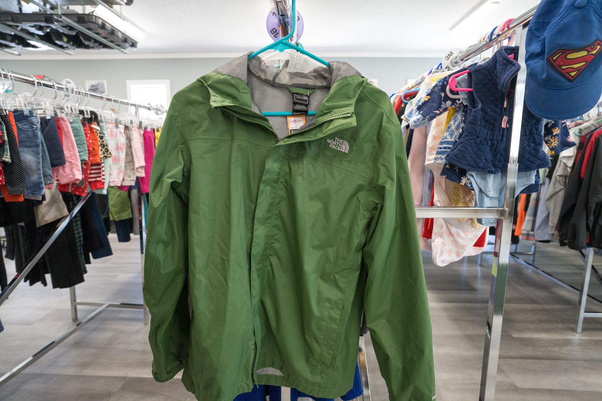 A green jacket is hanging on a hanger in a store.